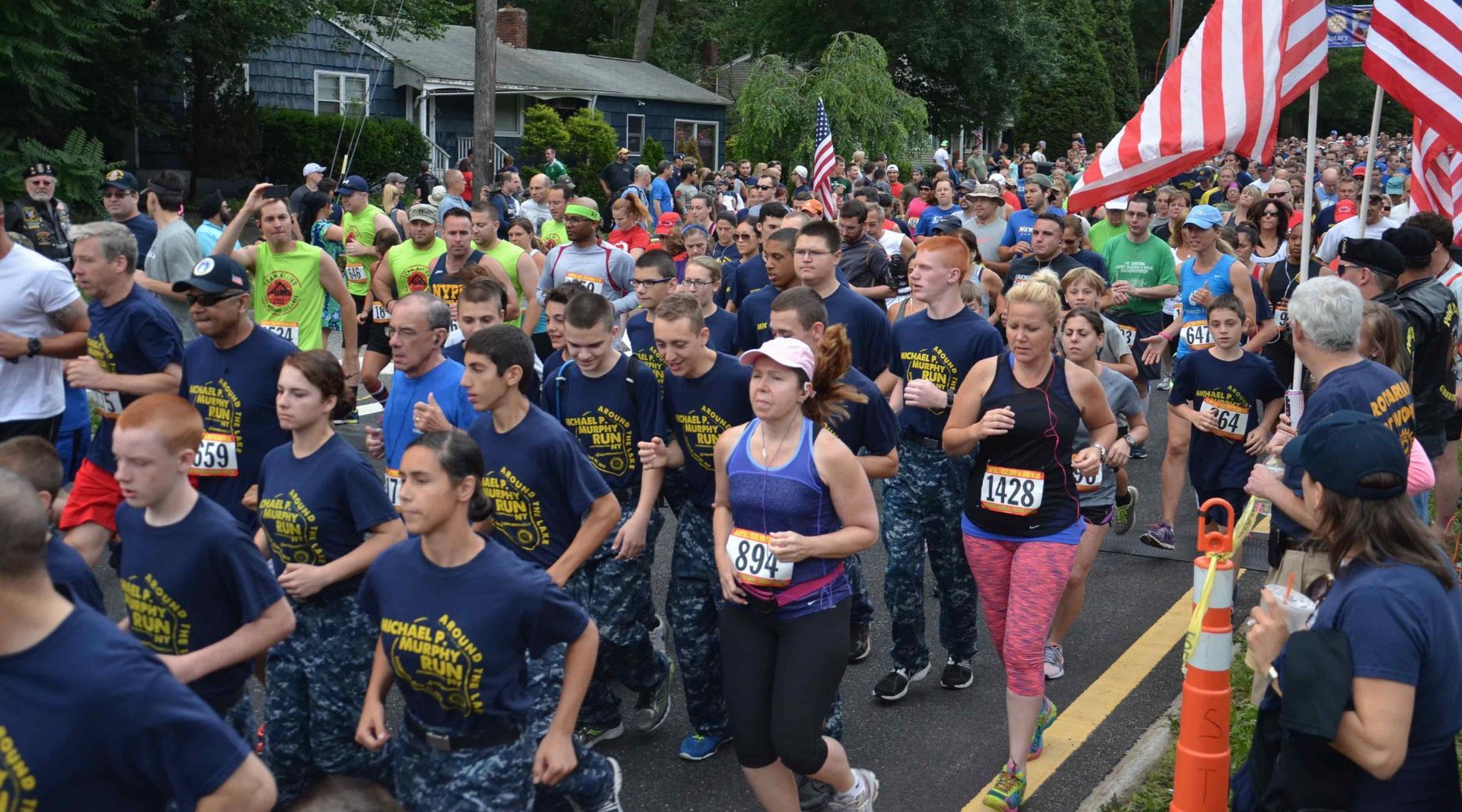 A group of people are running down a street and one of them has the number 157 on her shirt