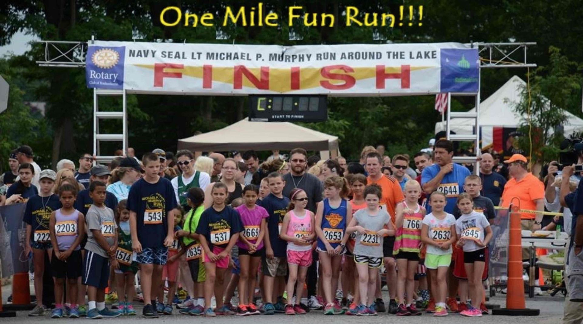A group of people standing in front of a sign that says one mile fun run