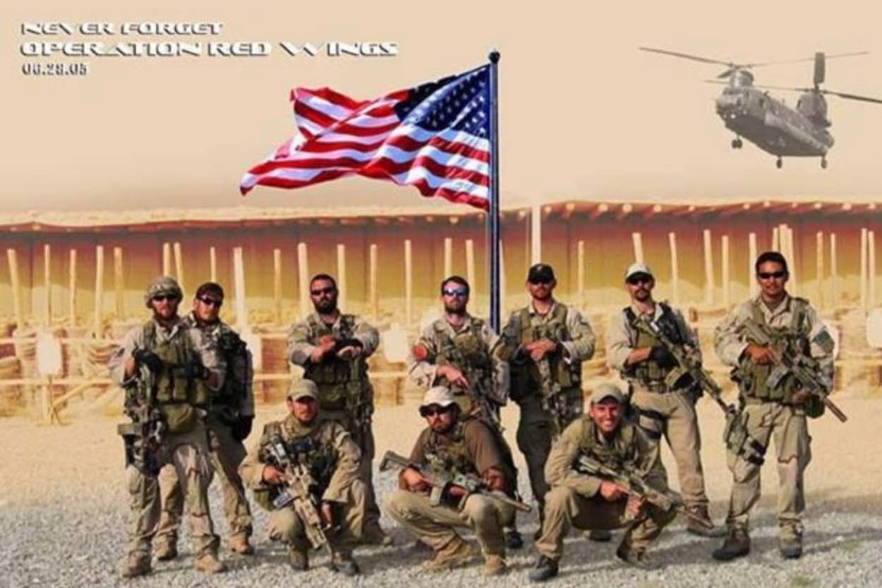 A group of soldiers pose in front of an american flag