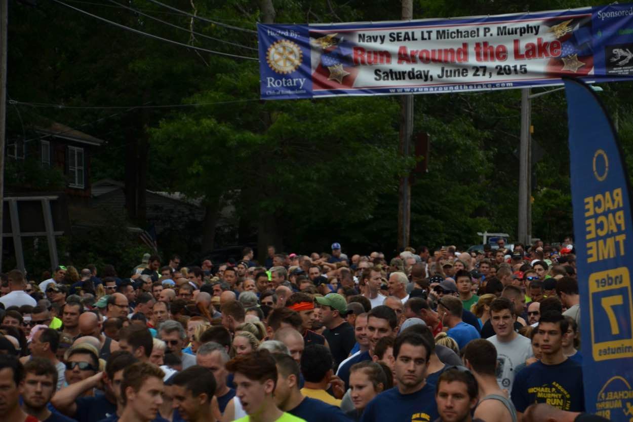 A large crowd of people are gathered in front of a sign that says 