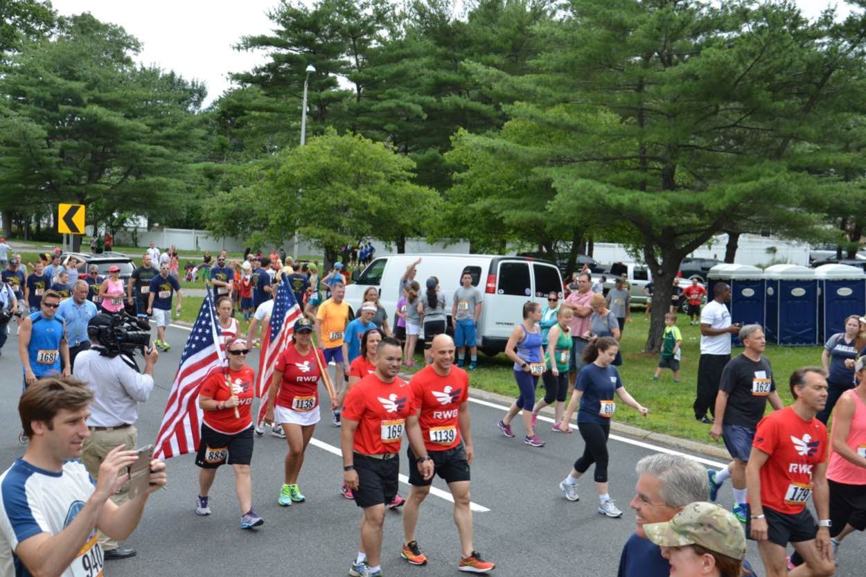 A group of people are walking down a street holding american flags