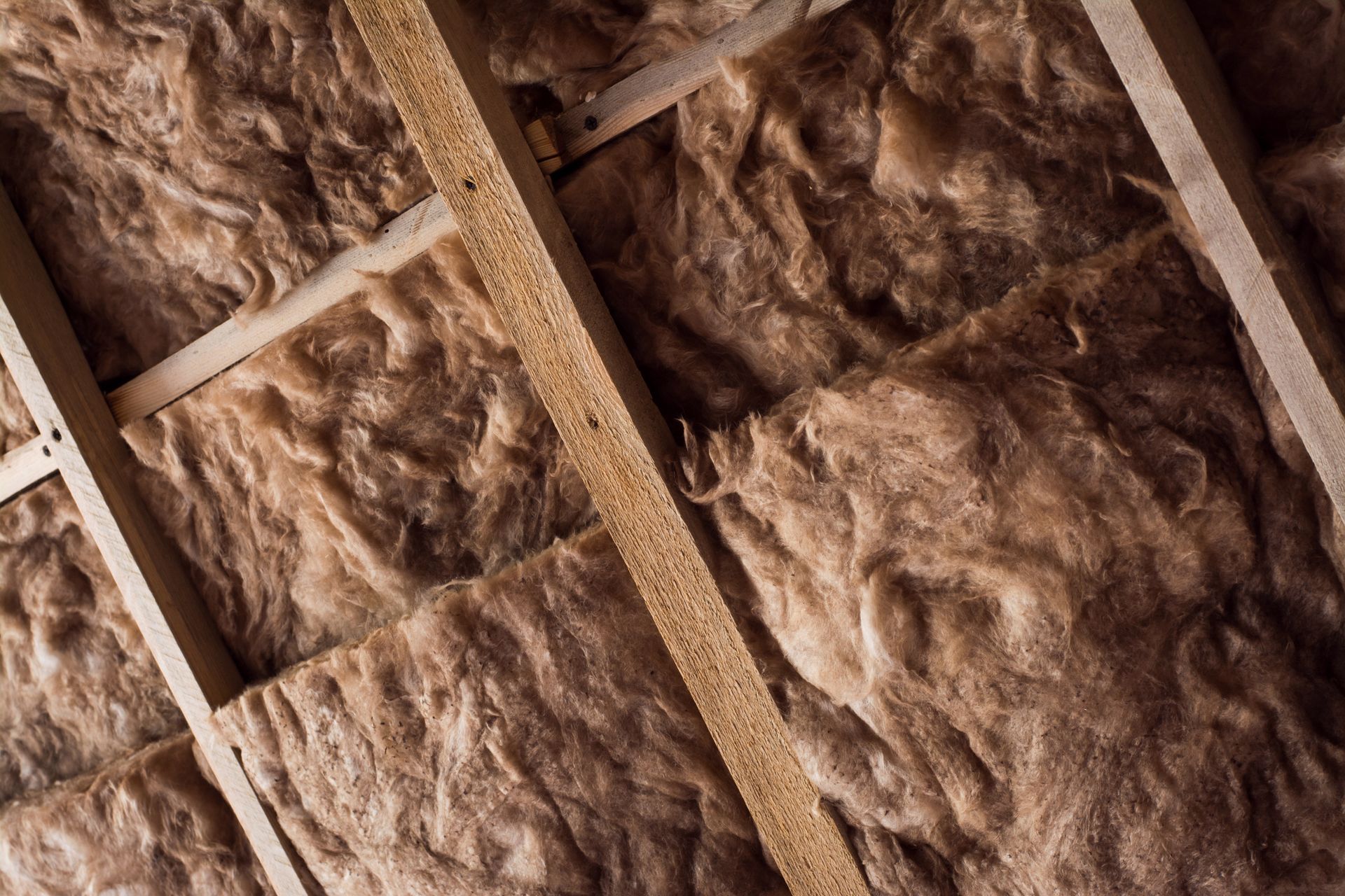 A close up of a ceiling with insulation and wooden beams.