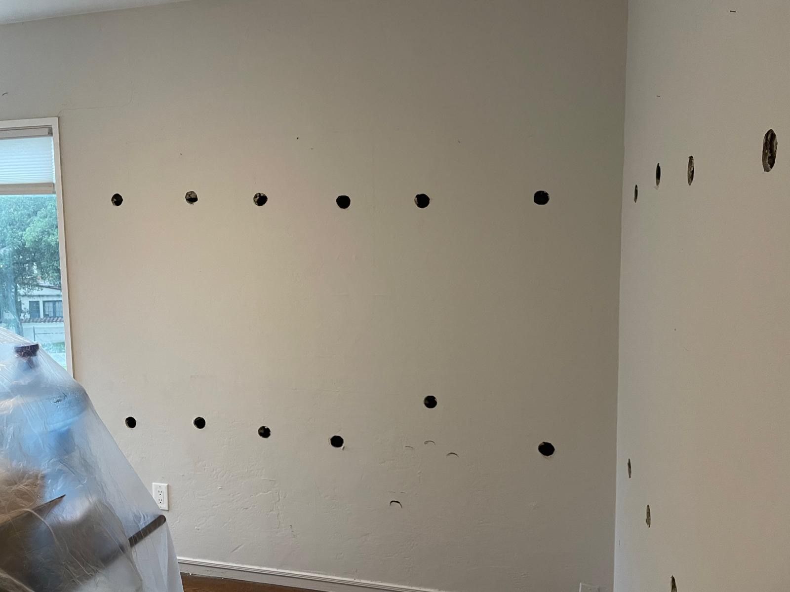 A room with holes in the wall and a window.