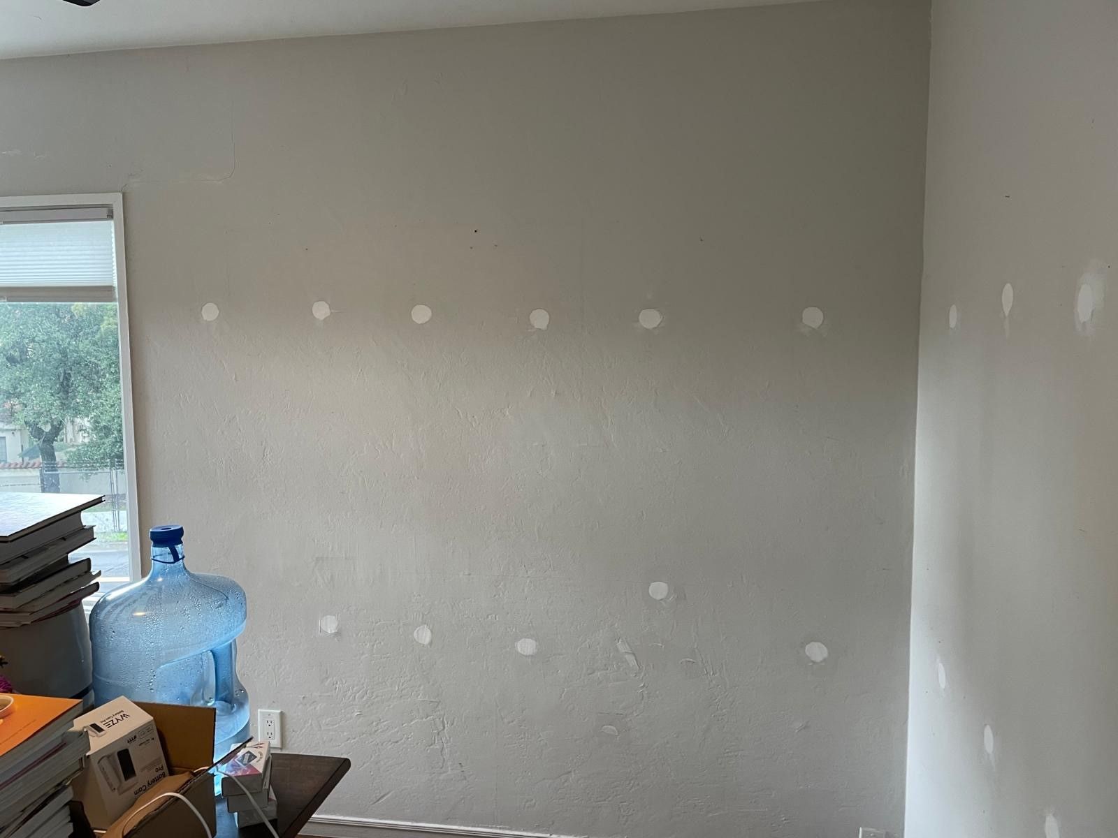 A person is spraying foam insulation on a wall.
