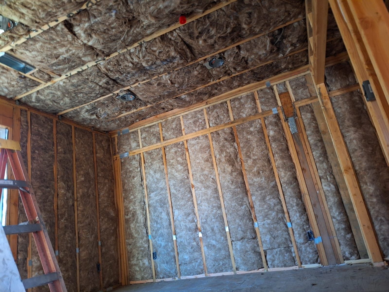 A room with a ladder and a lot of insulation on the walls and ceiling.