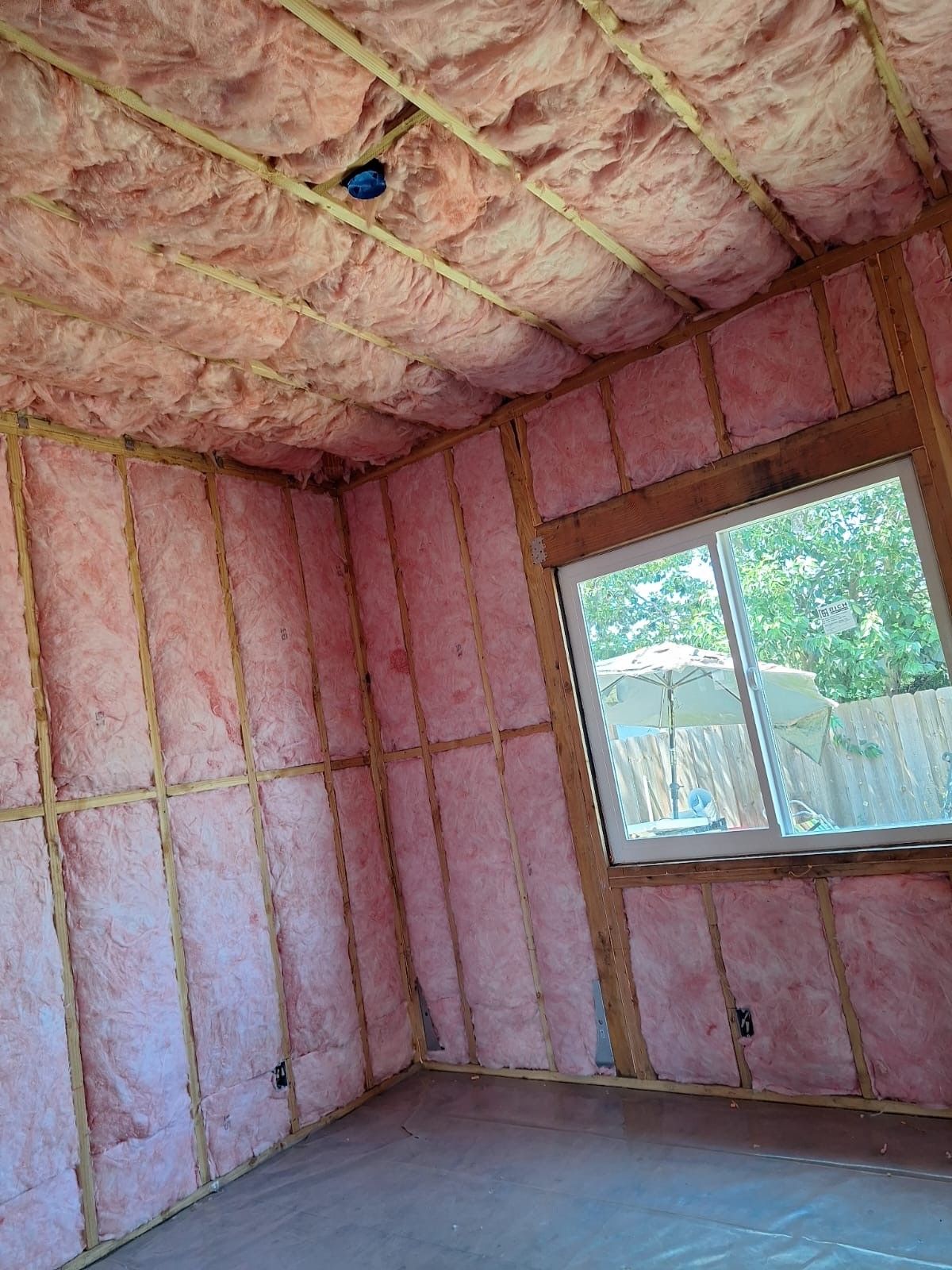 A room with pink insulation on the walls and ceiling and a window.