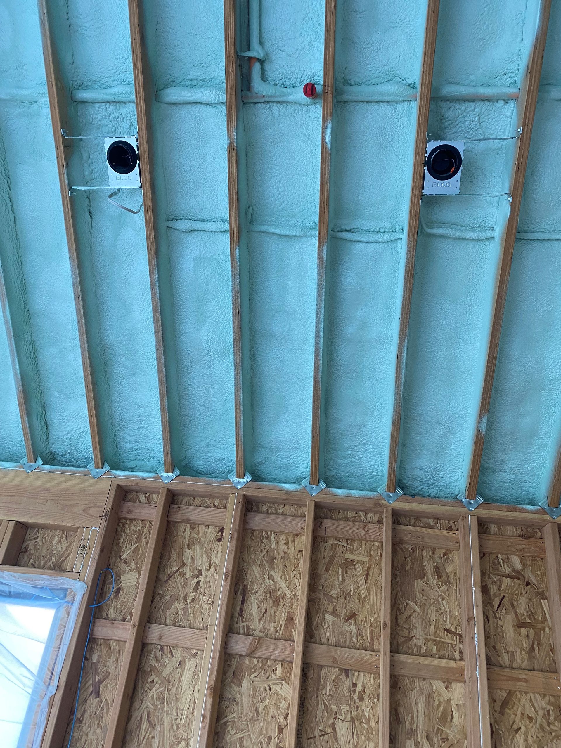 The ceiling of a house is being insulated with spray foam.
