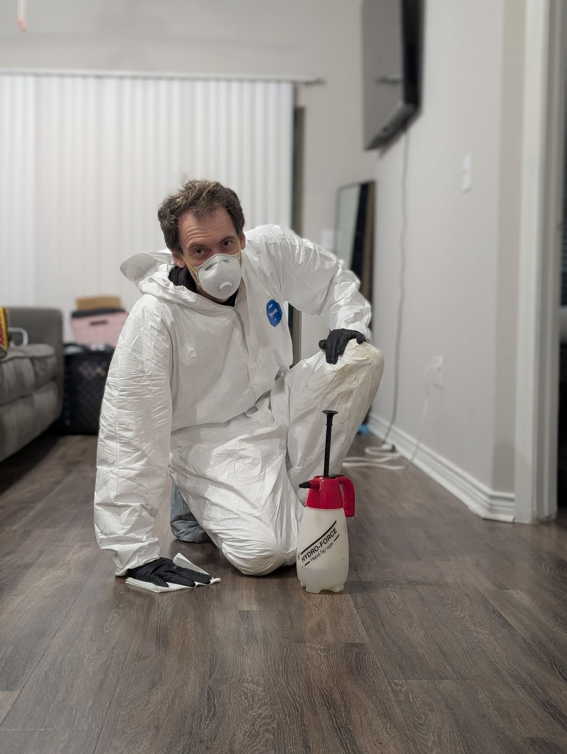 A person in a protective suit is cleaning a window in a living room.
