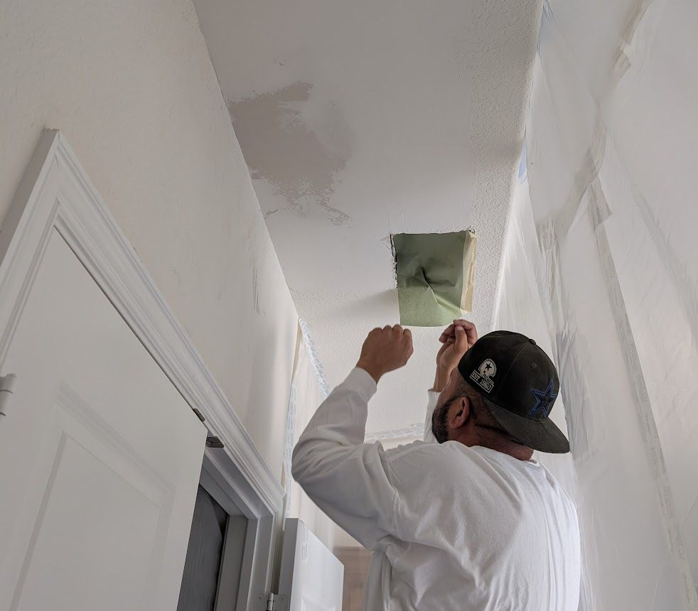 A man is working on the roof of a house next to a truck that says ' roofing ' on it