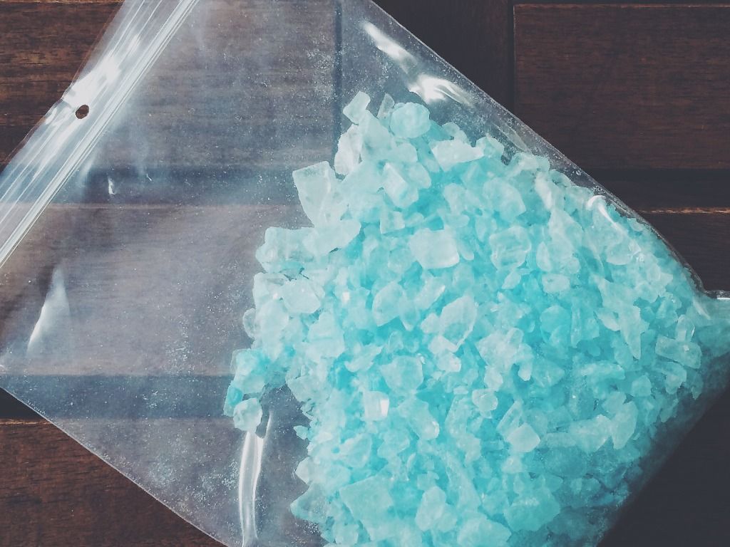 A plastic bag filled with blue crystals on a wooden table