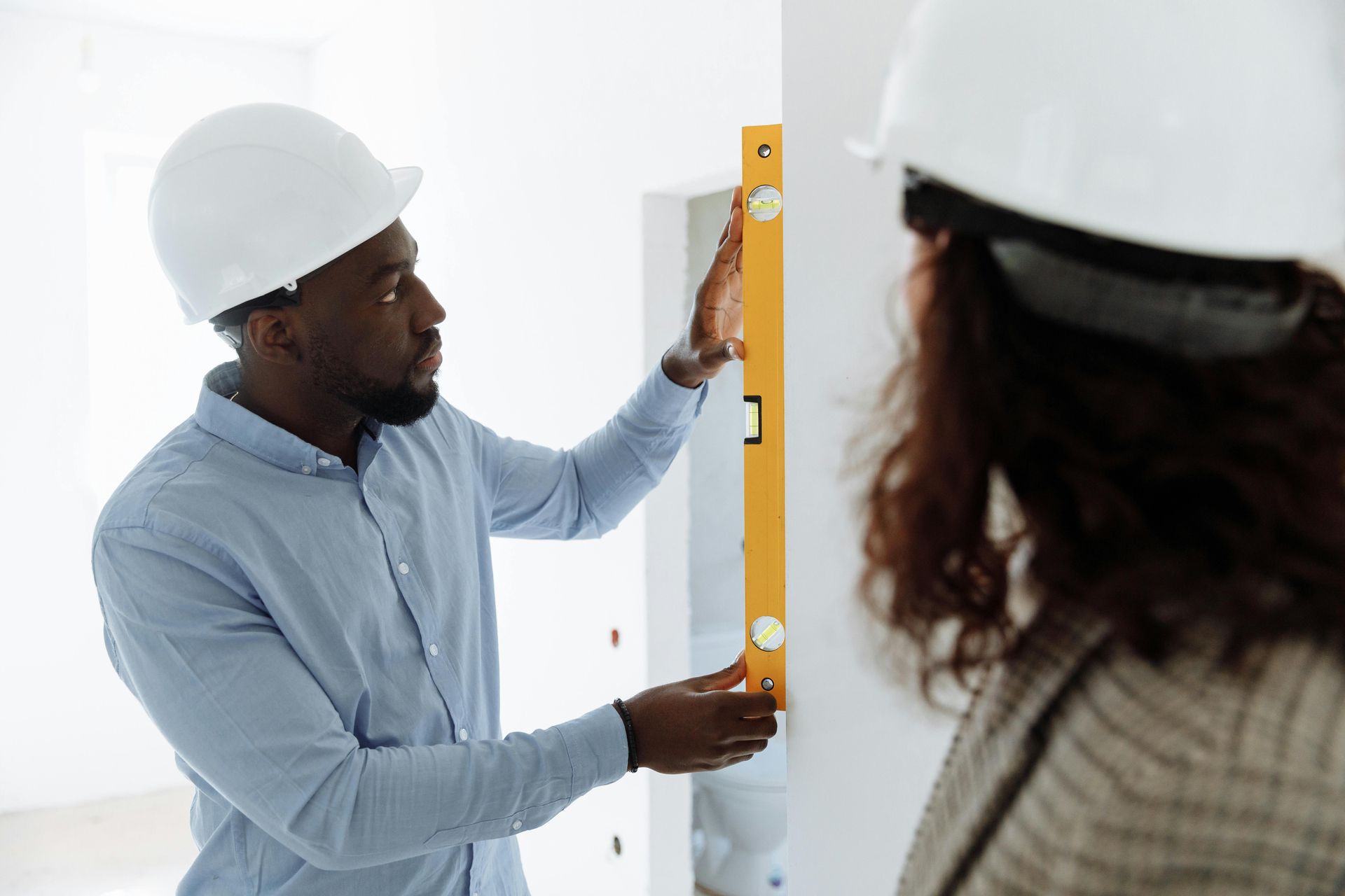 A man and a woman are measuring a wall with a level.