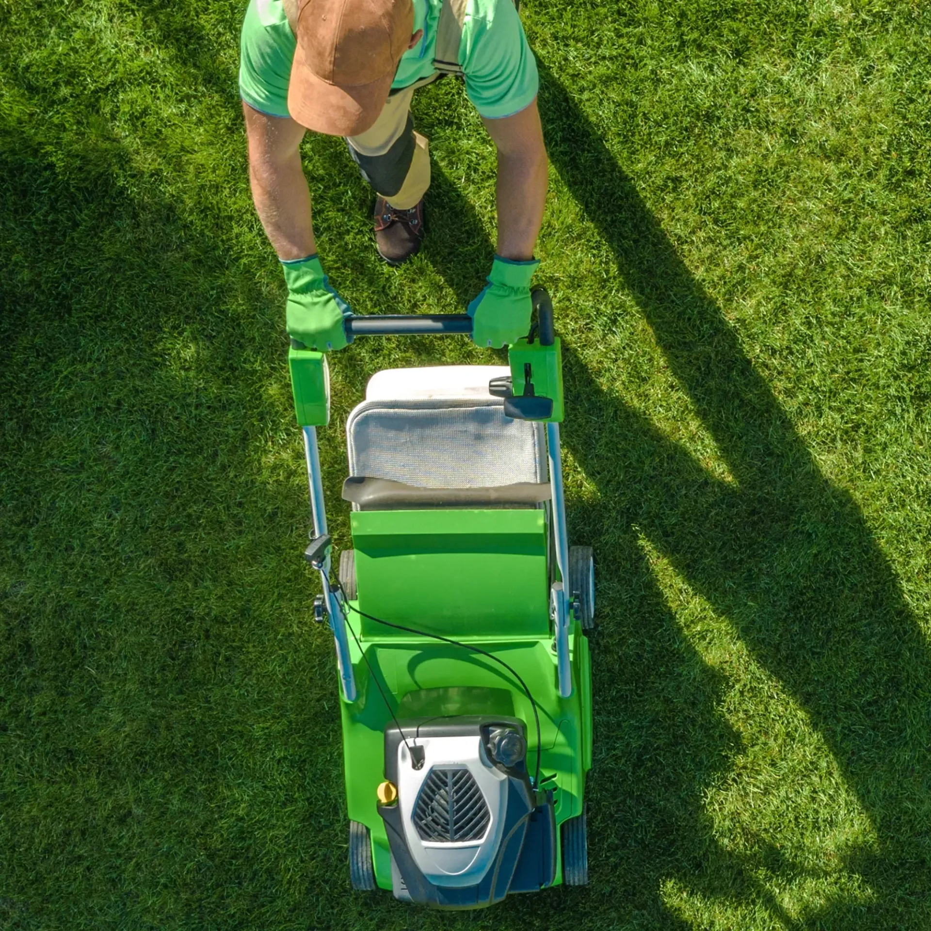 Brothers Landscaping - An aerial view of a man cutting a lush green lawn with a green lawn mower.