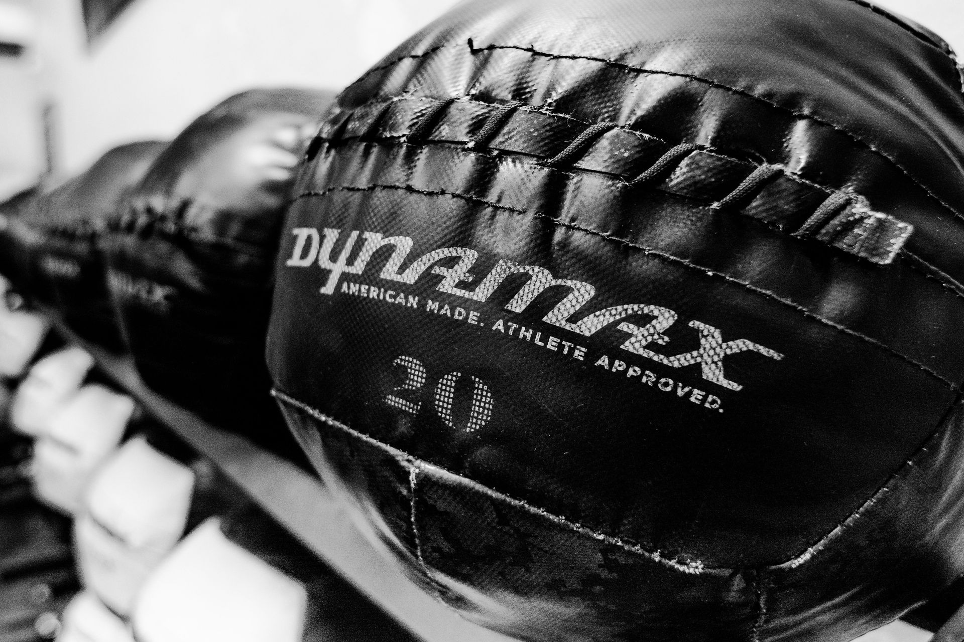 Schwarz-Weiß-Foto eines Dynamax-Medizinballs, auf dem das „Dynamax“-Logo und die Gewichtsangabe „20“ erkennbar sind.