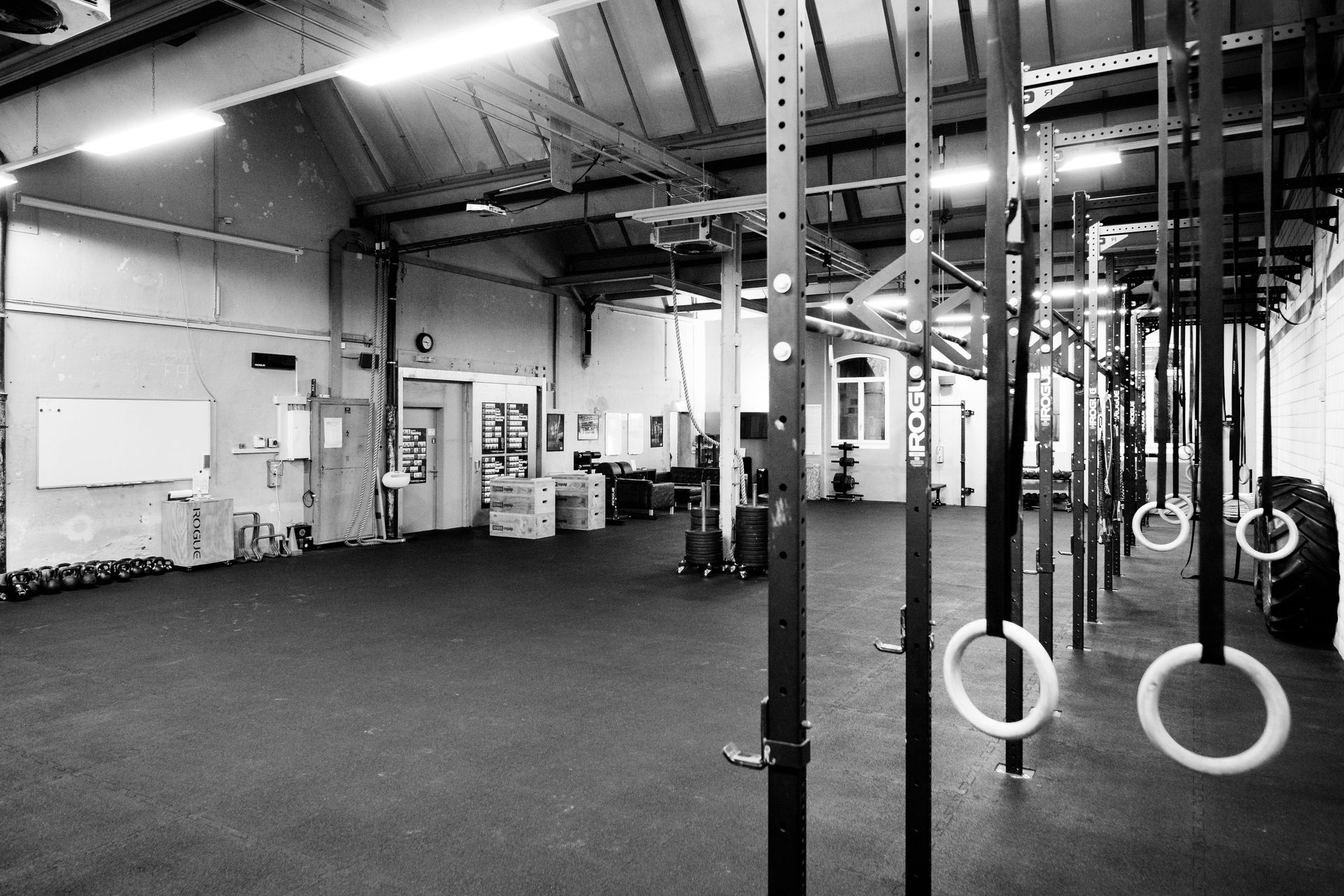 Fitnessstudio-Interieur mit Turnringen, dunklem Boden und Trainingsgeräten.