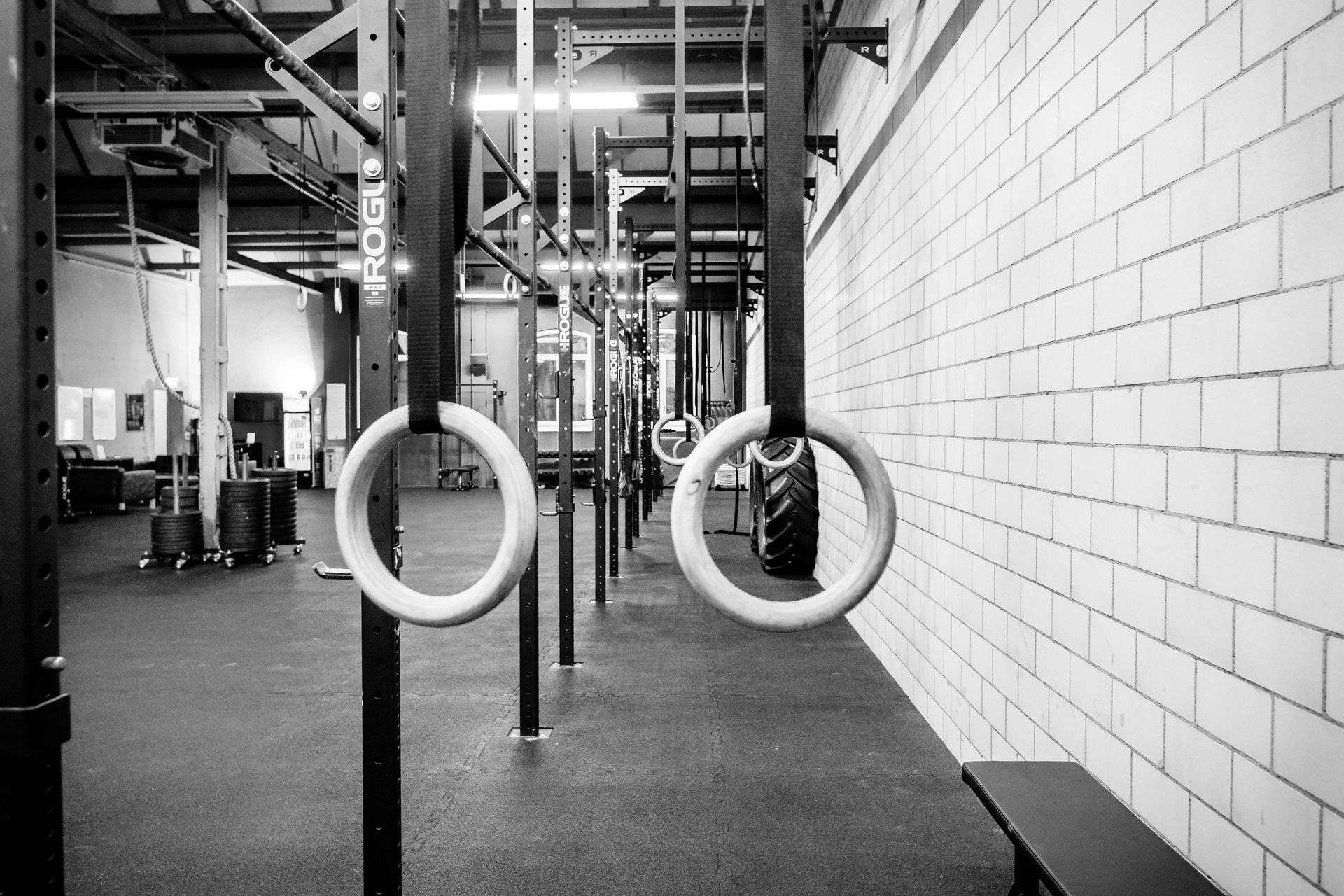 Turnhalleninterieur mit hängenden Ringen, Geräten und Backsteinwand. Schwarz-Weiß.