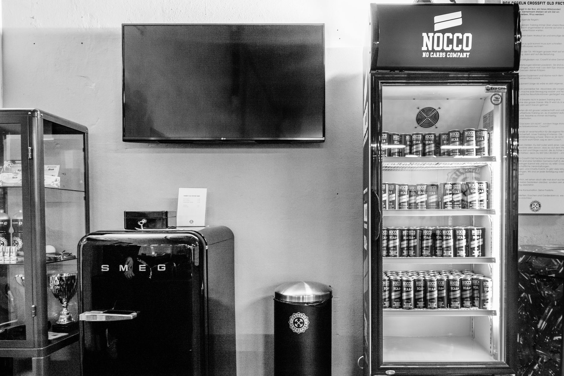 Innenansicht eines Ladens mit einem mit Dosen gefüllten Getränkekühler, einem Fernseher und einem Verkaufsautomaten.