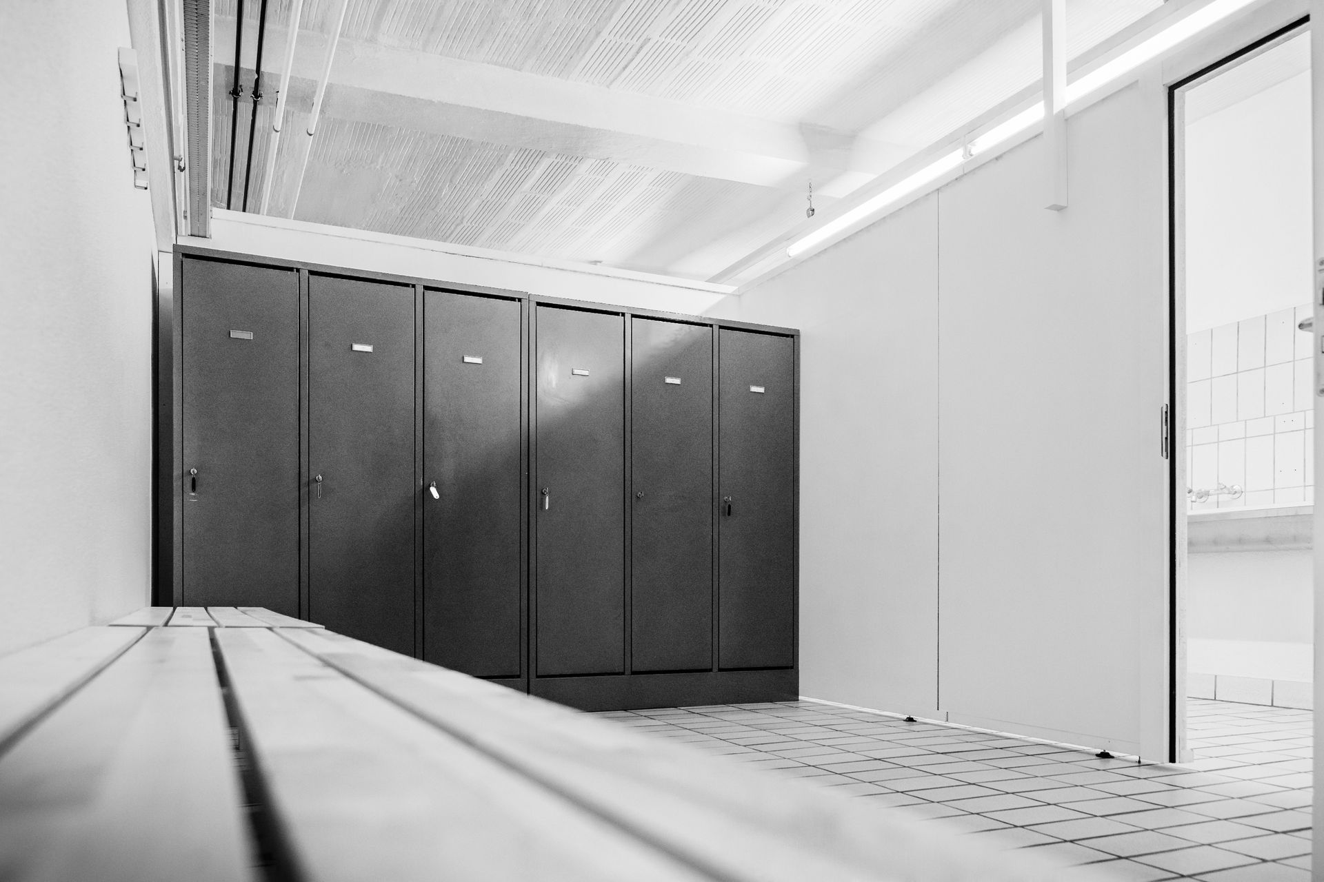 Schwarz-Weiß-Aufnahme von Spinden in einem Raum mit einer Bank.