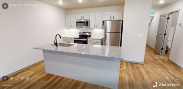 Modern kitchen with gray cabinets, black appliances, and a white countertop island.
