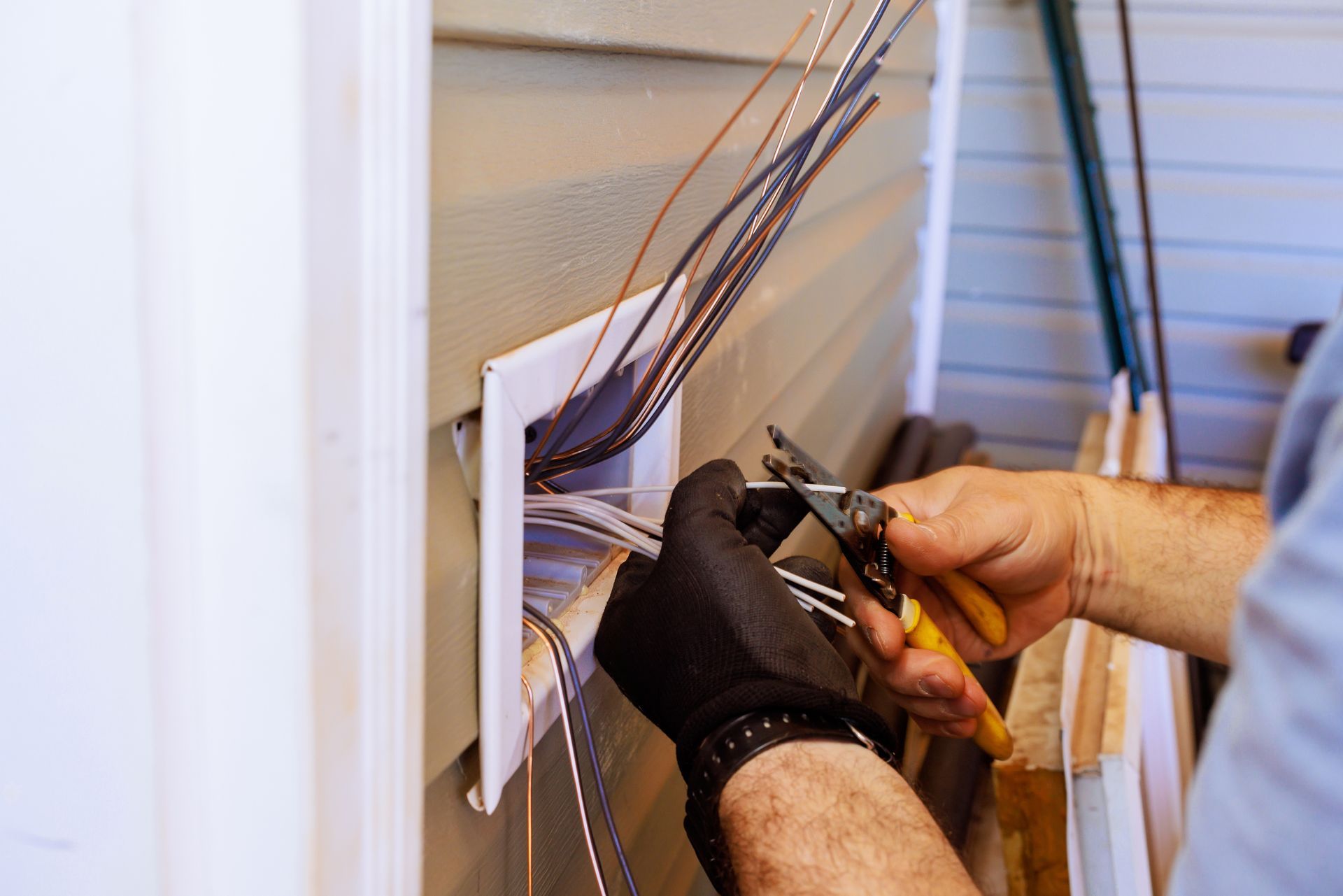 An electrician carefully strips wires while installing electrical connections.