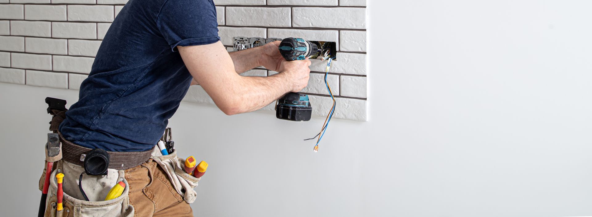Electrician installing a wall outlet during professional work by electrical services contractors.