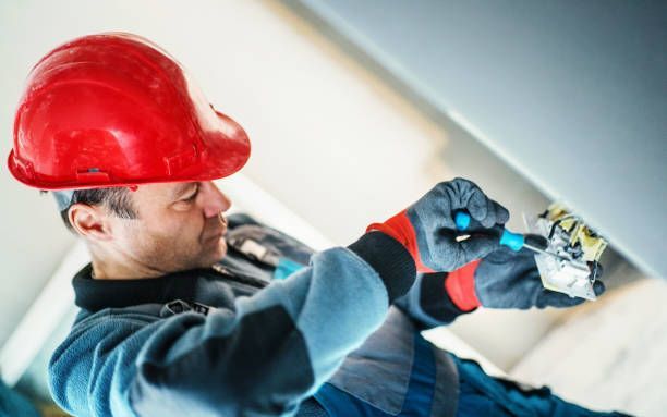 A professional electrician provides electrical services by installing a new light switch in a home.