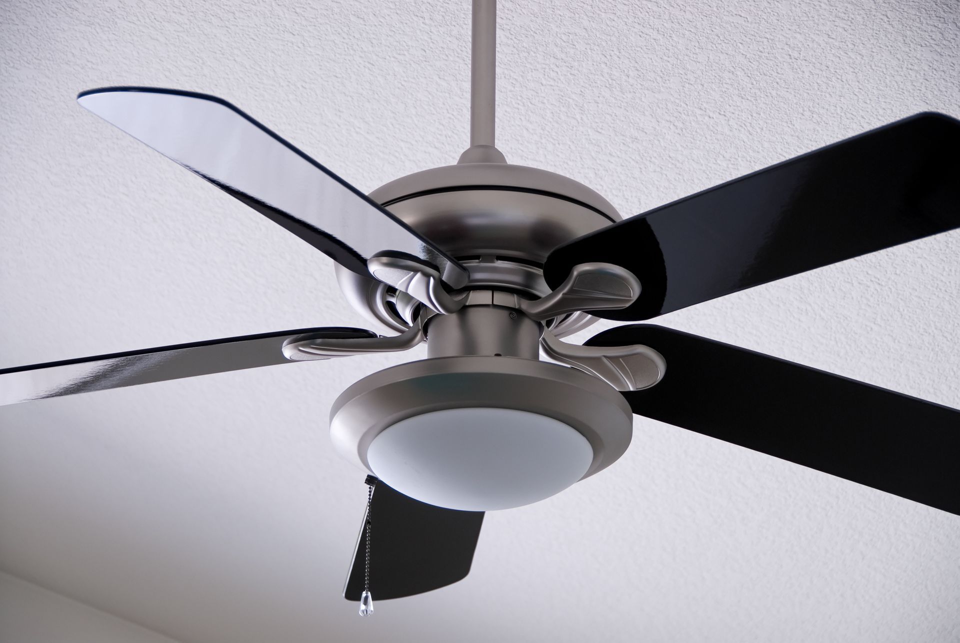 A close up of a ceiling fan with black blades