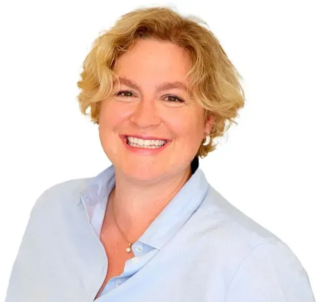 Zahnärztin Christina Krause  (Zahnarzt in Sülldorf) in einem blauen Hemd lächelt in die Kamera.