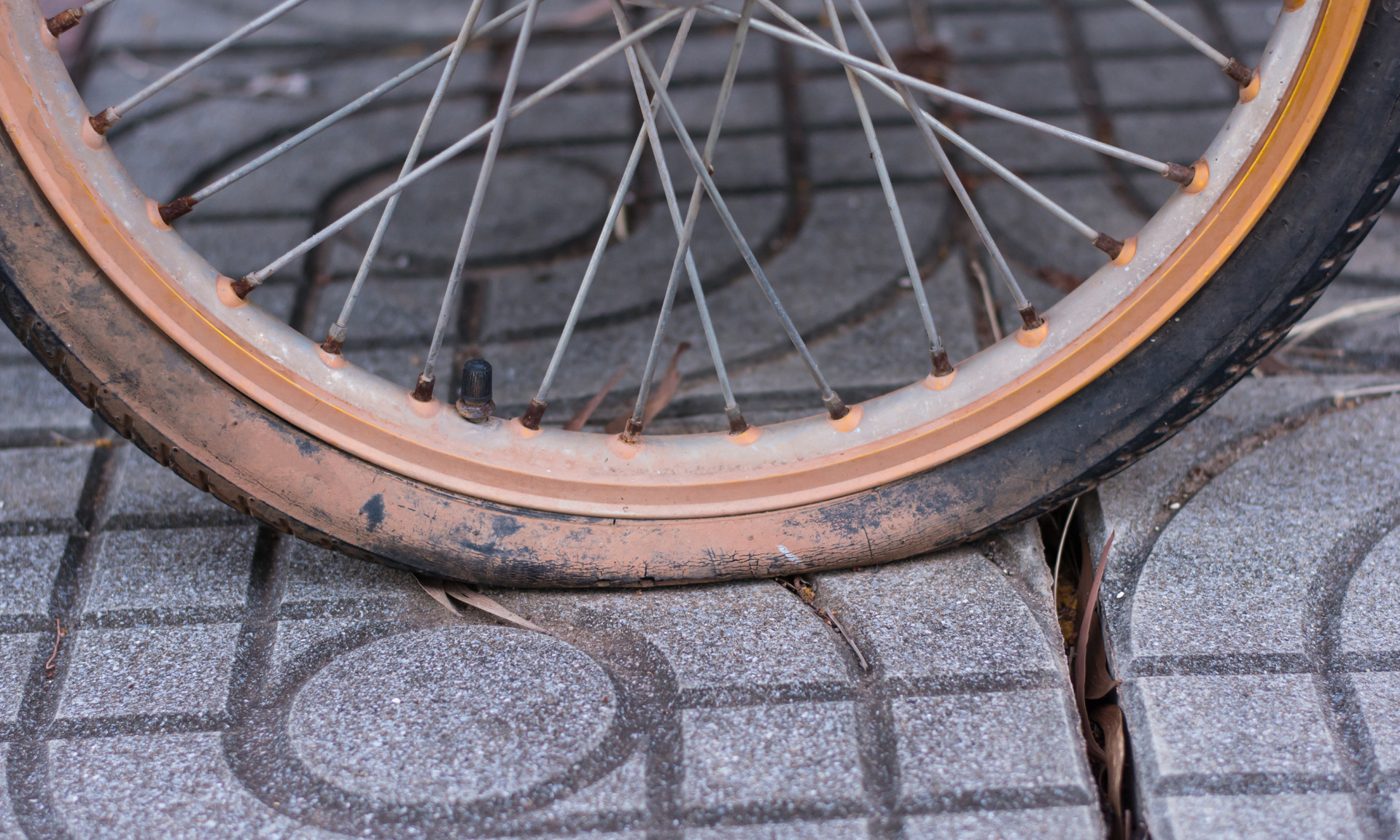 Een lekke fietsband op de stoep. De band is bruin en leeggelopen.