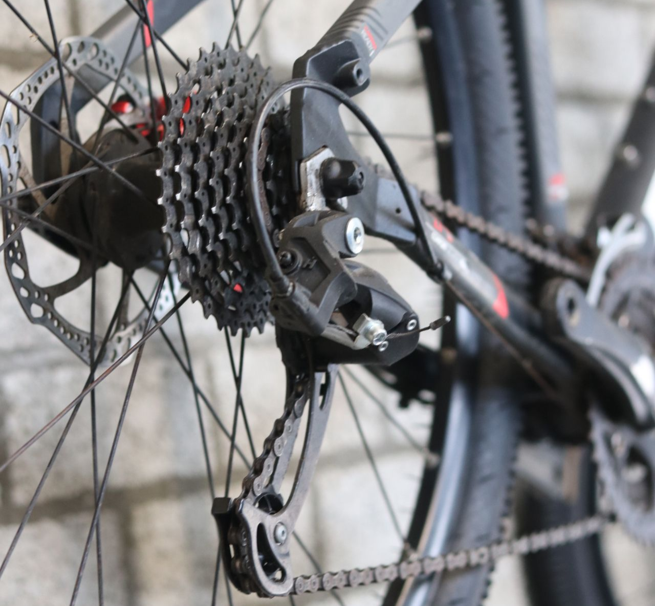 Achterwiel van een fiets met versnellingen, schijfrem en derailleur.