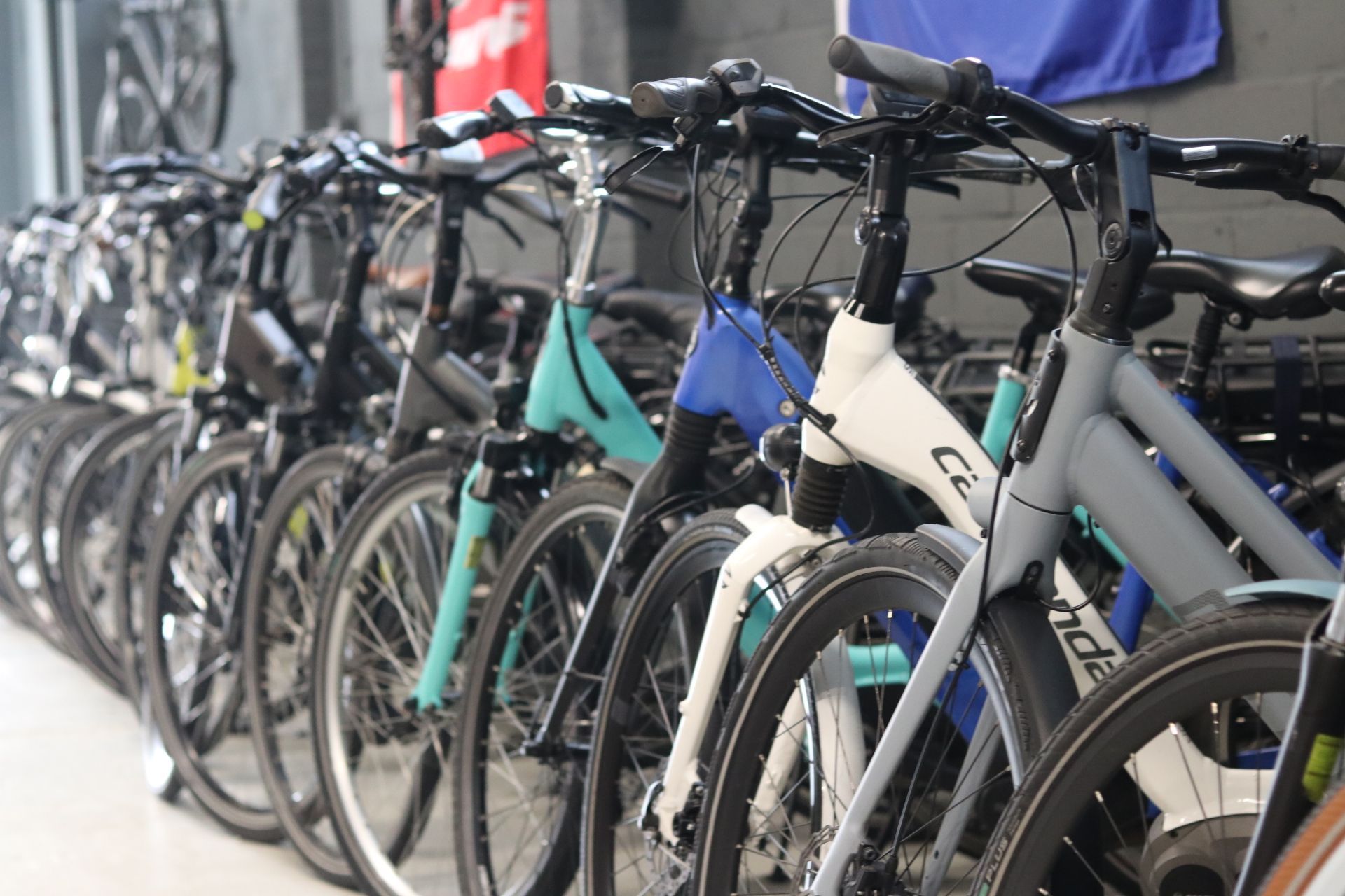 Een rij fietsen in een winkel, in verschillende kleuren zoals turquoise, blauw en grijs, met zichtbare sturen.