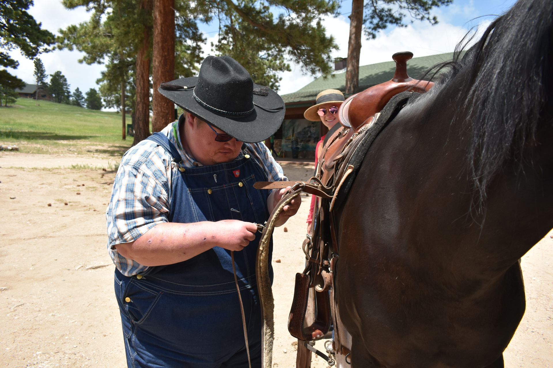 Camp Hope camper helping with horse saddle.