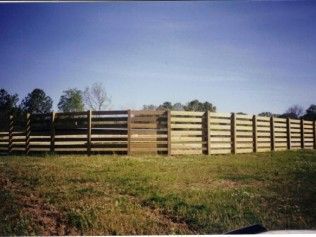Wooden horse fence in a grassy field against a blue sky
