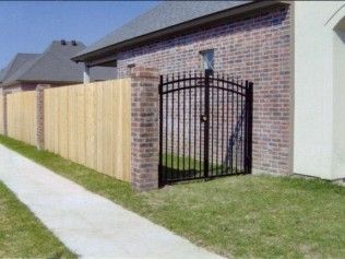 Brick wall and wooden fence with a black wrought iron gate