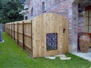 Wooden fence with a gate next to a brick building