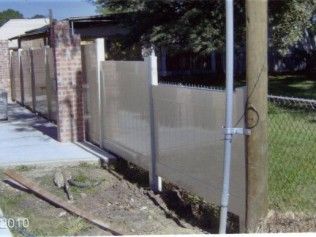 Metal fence with brick wall and utility pole along a sidewalk