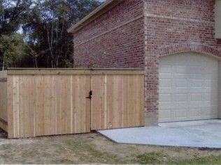 Wooden fence with gate next to a brick building and garage door