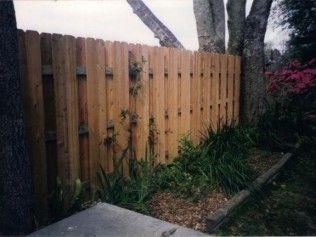 Wooden fence in front of greenery and trees