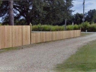 Wooden fence bordering a gravel driveway next to a grassy area