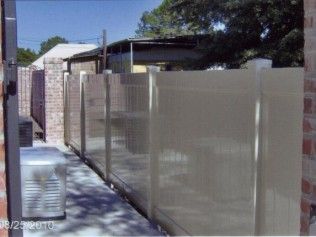 Beige vinyl fence with brick columns and a sliding gate