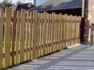 Wooden picket fence next to a brick wall