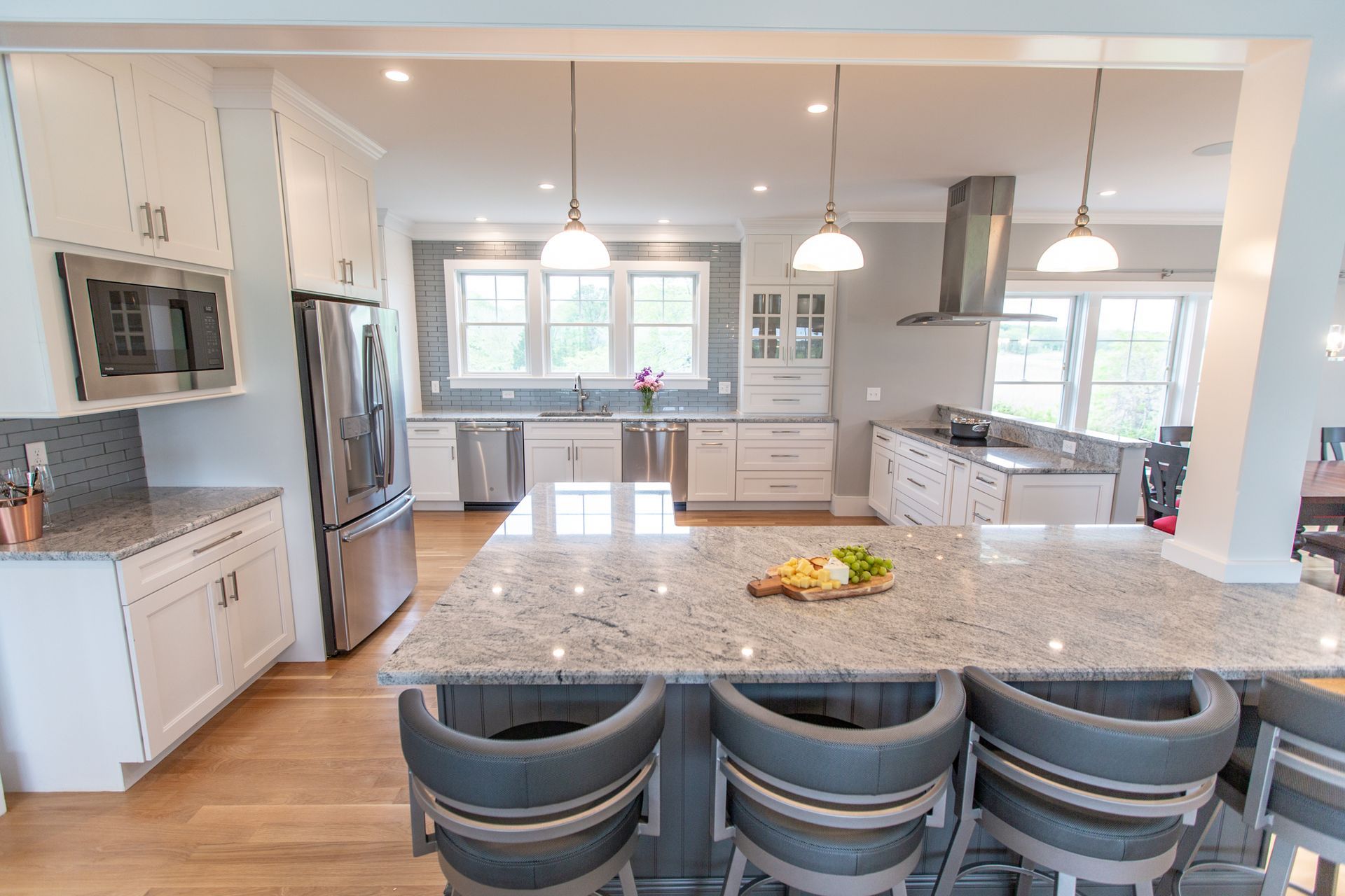 Bright modern kitchen with large island, pendant lights, white cabinets, and stainless steel appliances