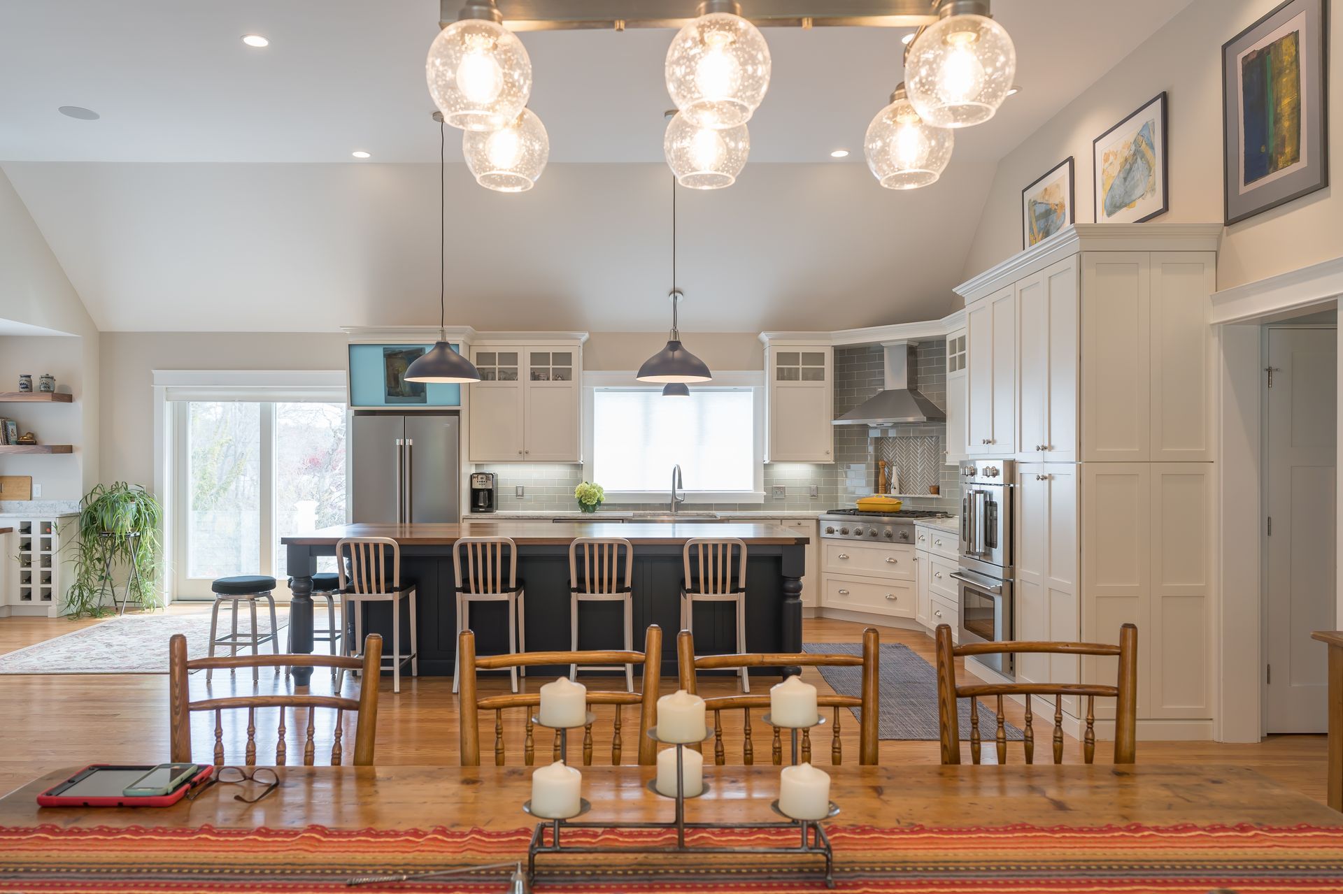 Bright open kitchen and dining room with wooden table, chairs, island, and pendant lights