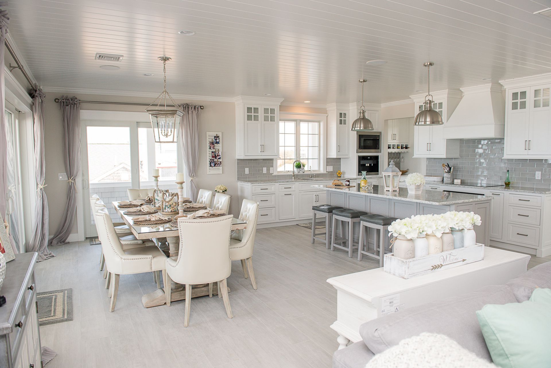 Bright white open-plan kitchen and dining room with table, island, and large windows