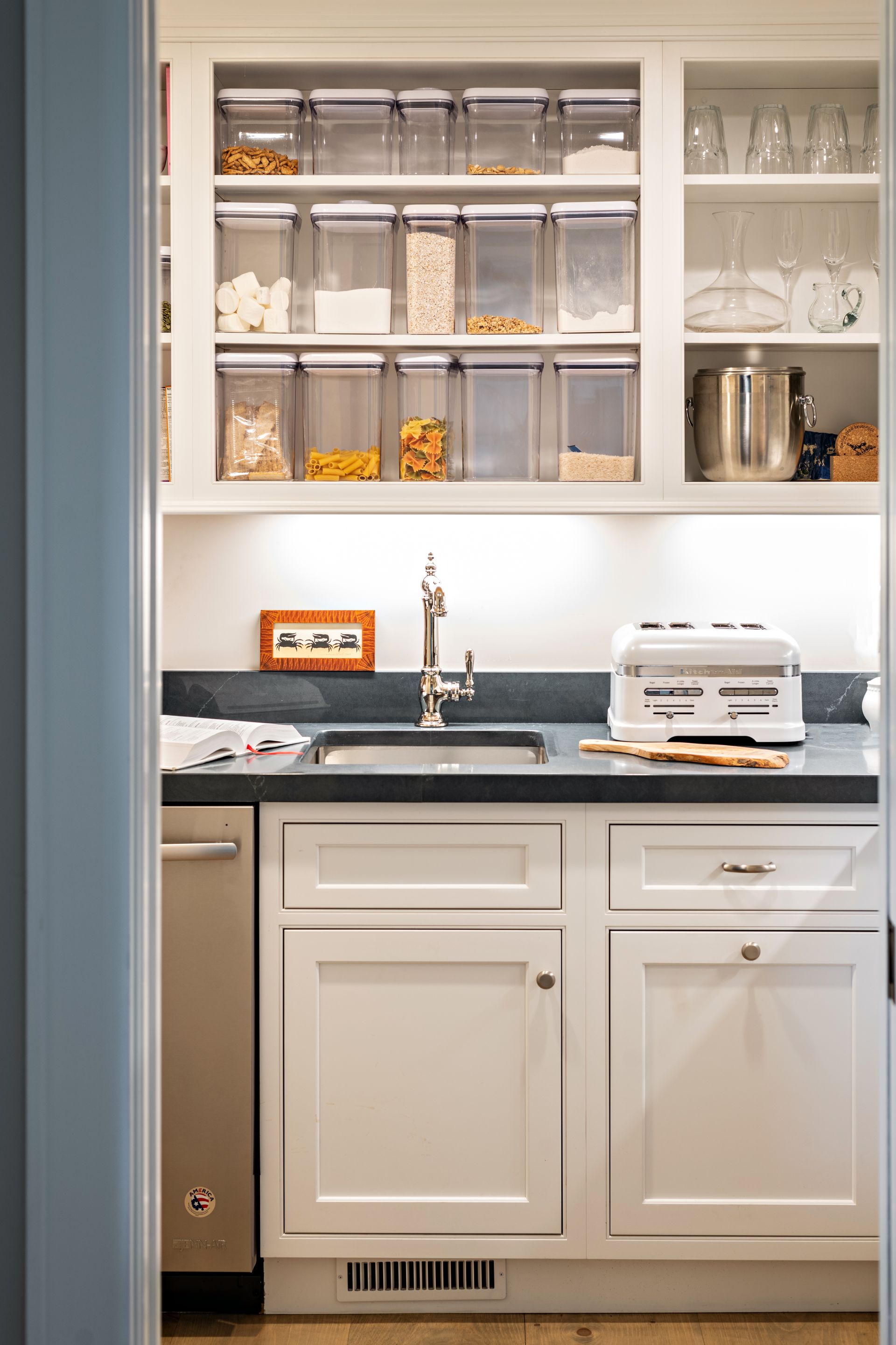 Bright kitchen cabinets with open shelving, countertop sink, and toaster below under-cabinet lighting