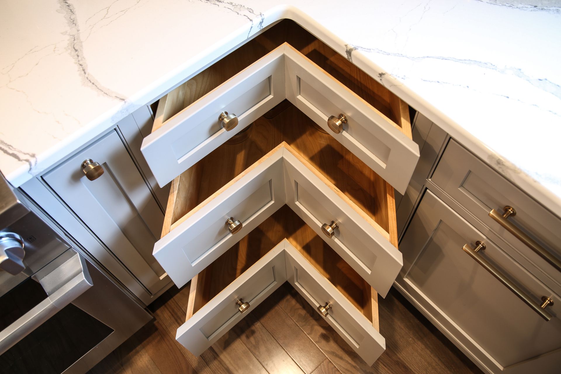 Open corner kitchen drawers with white and wood cabinetry showing organized storage interiors