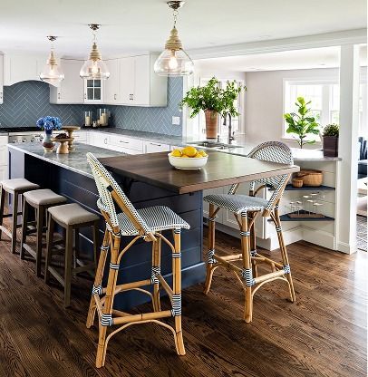 Bright modern kitchen with dark island, wicker stools, pendant lights, and a bowl of lemons.
