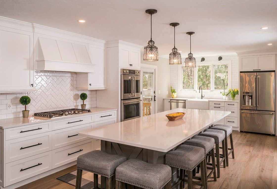 Modern white kitchen with large island, pendant lights, and stainless steel appliances