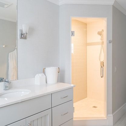 Bright bathroom with vanity, sink, mirror, and an open lit shower stall.