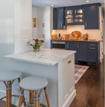 Bright kitchen with navy cabinets, white island, bar stools, and warm lighting