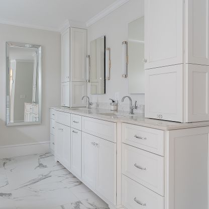 Bright white bathroom vanity with double sinks, mirrors, and marble floor and countertop
